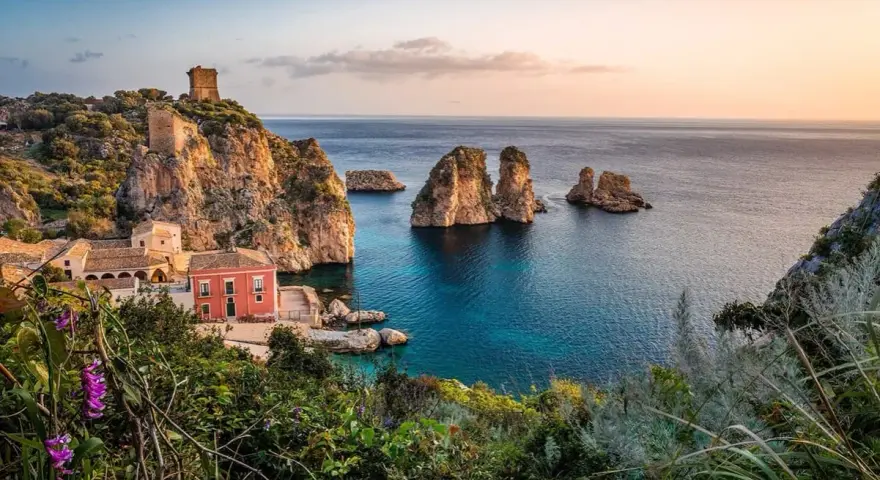 Traumhafte Küstenlandschaft mit Felseninseln, einem alten Turm und einem roten Haus. Perfekt für ein Auslandsjahr in Italien.