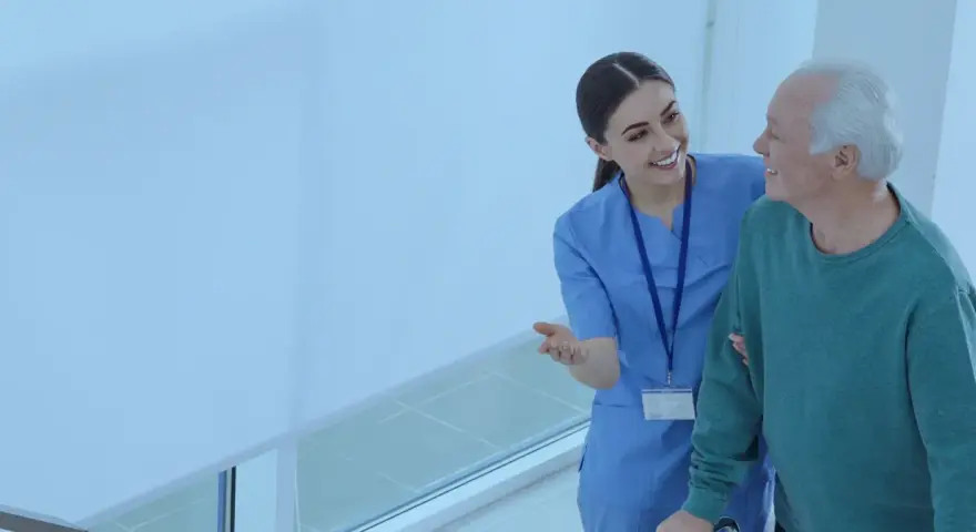Enfermera sonriente ayuda a un anciano a caminar. El **fp tcae** de la atención médica se refleja en su mirada.