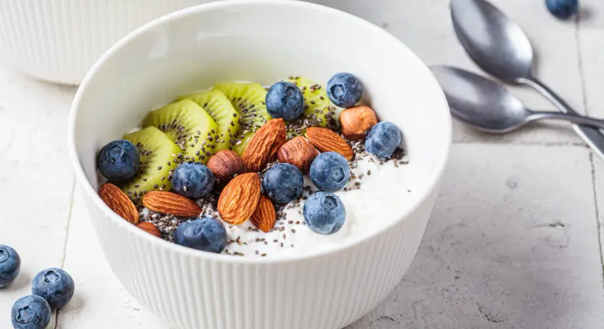 Schüssel mit Magerquark, Blaubeeren, Kiwi, Mandeln und Chiasamen. Perfekt für gesunde Magerquark Rezepte.