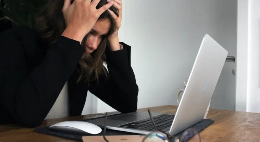 Femme stressée devant son ordinateur, les mains sur la tête, face à une saisie administrative à tiers détenteur.