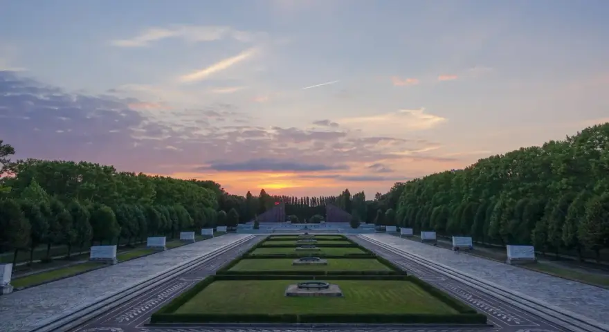 Sonnenuntergang über dem Sowjetischen Ehrenmal in Berlin. Ein beeindruckendes Beispiel für Parks in Berlin, mit symmetrischen Rasenflächen und einer langen Allee.