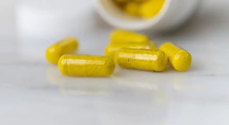 Capsule gialle sparse su una superficie chiara. La berberina a cosa serve? Potrebbe essere la risposta in queste capsule.