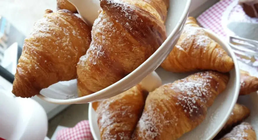 Cornetti fatti in casa, dorati e spolverati di zucchero a velo, invitano a una colazione golosa.