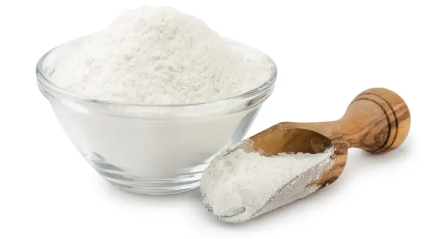 Una ciotola di vetro piena di polvere bianca, probabilmente aluminum starch octenylsuccinate, e un cucchiaio di legno con la stessa polvere.