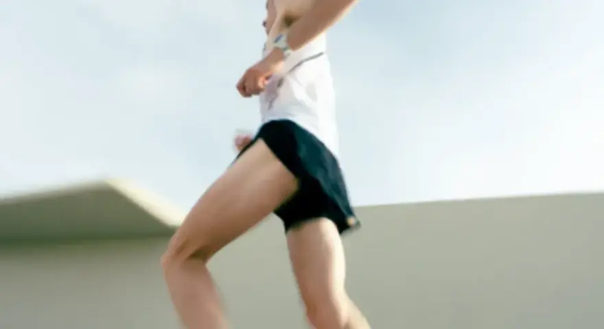Un atleta corre a tutta velocità, mostrando quanto corre veloce un uomo. Le gambe muscolose si muovono rapidamente, catturando l'essenza della velocità.