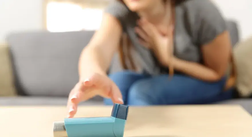 Kobieta z atakiem astmy sięga po inhalator z fenoterolem.