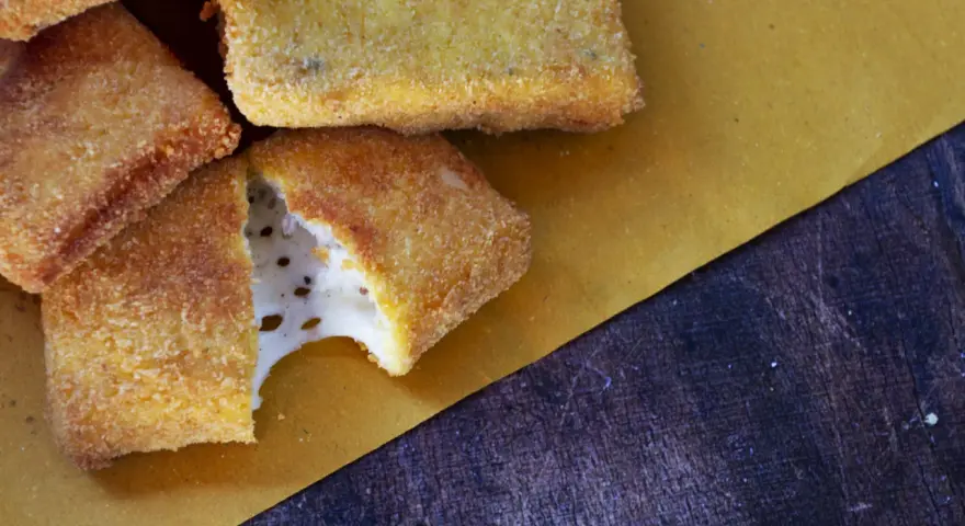 Mozzarella in carrozza dorata e croccante, con il formaggio filante che fuoriesce da uno dei pezzi.