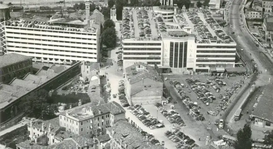 Vista aerea del parcheggio San Andrea a Venezia, con file di auto parcheggiate su più livelli e un edificio INA.