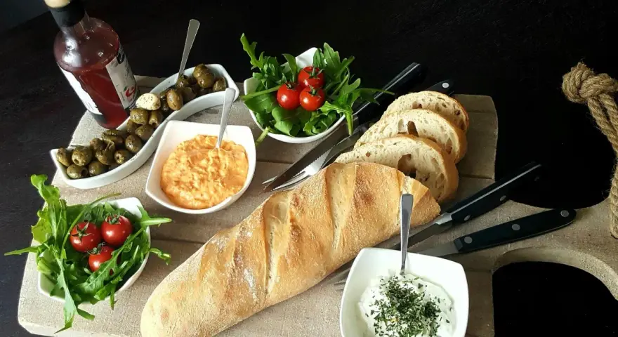 Eine köstliche italienische Brotzeit mit Baguette, Oliven, Tomaten, Rucola und Dips.