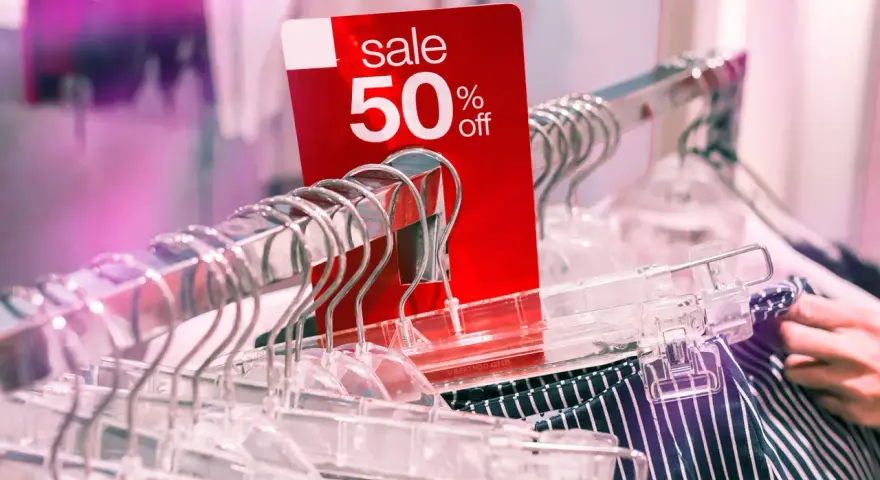 Czerwona metka "sale 50% off" na wieszakach. Czy to początek kompulsywnych zakupów?