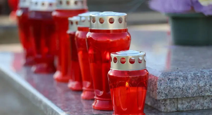 Rote Grablichter brennen auf einem Grabstein. Am 1. November, dem Feiertag Allerheiligen, werden sie zum Gedenken entzündet.