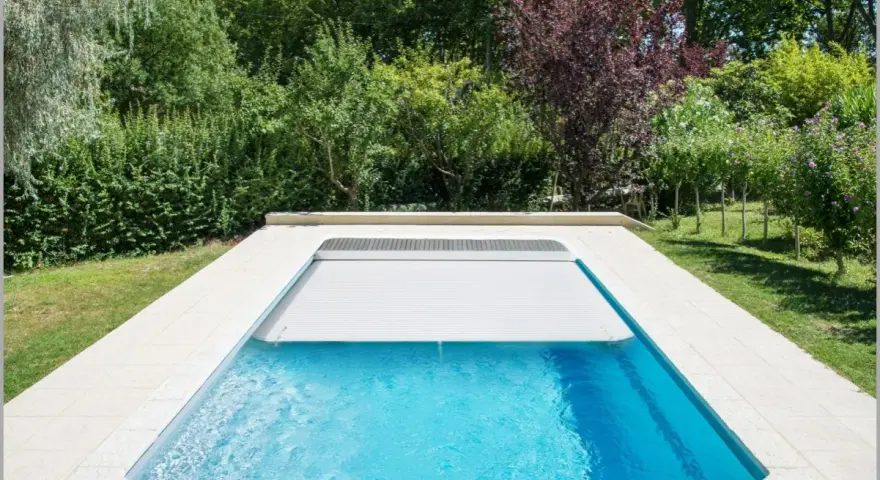 Piscina con cubierta automática, lista para reformar y disfrutar del verano. Rodeada de vegetación exuberante.