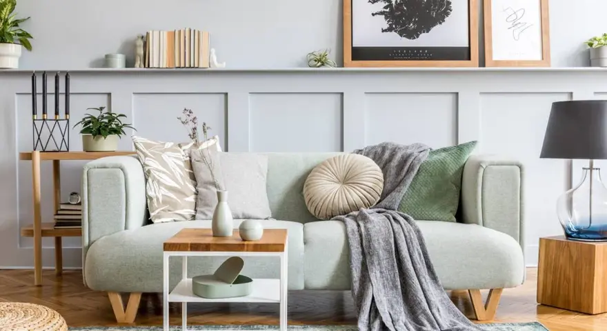 Un plaid gris drapé sur un canapé vert menthe, ajoutant une touche cosy. Idée pour comment mettre un plaid sur un canapé.