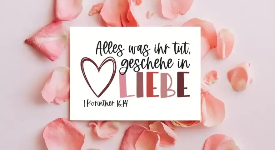 Herzförmige Karte mit dem Spruch "Alles was ihr tut, geschehe in LIEBE. 1.Korinther 16:14", umgeben von zarten rosa Blütenblättern.