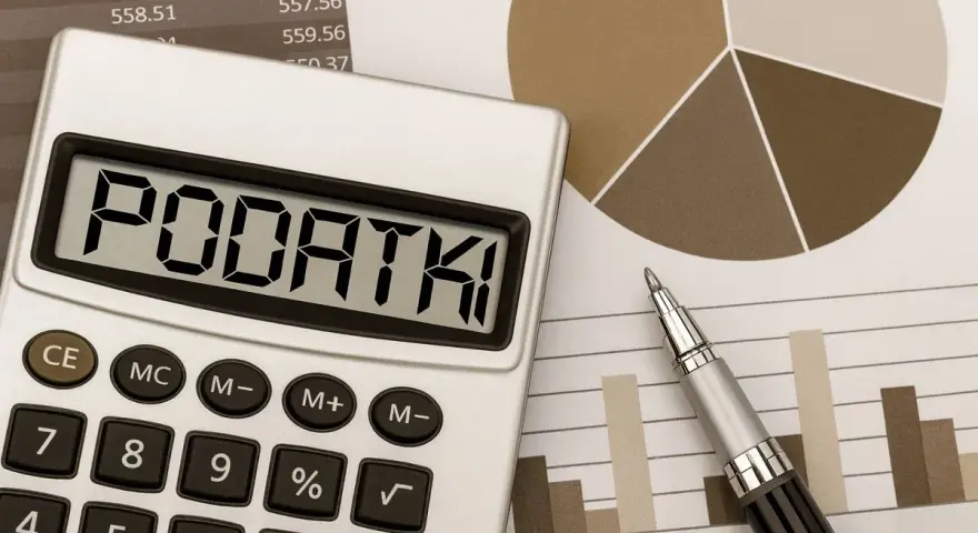 Kalkulator z napisem "PODATKI" obok wykresów i długopisu. Obrazek sugeruje analizę finansową, być może dotyczącą podatku od sprzedaży nieruchomości po upływie 5 lat.