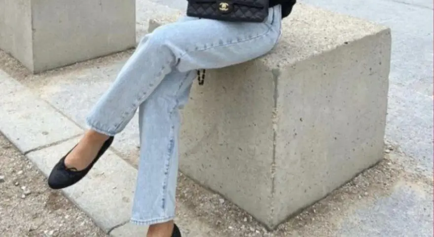 Un look chic pour savoir avec quoi porter des ballerines : jean clair, veste noire et sac matelassé.