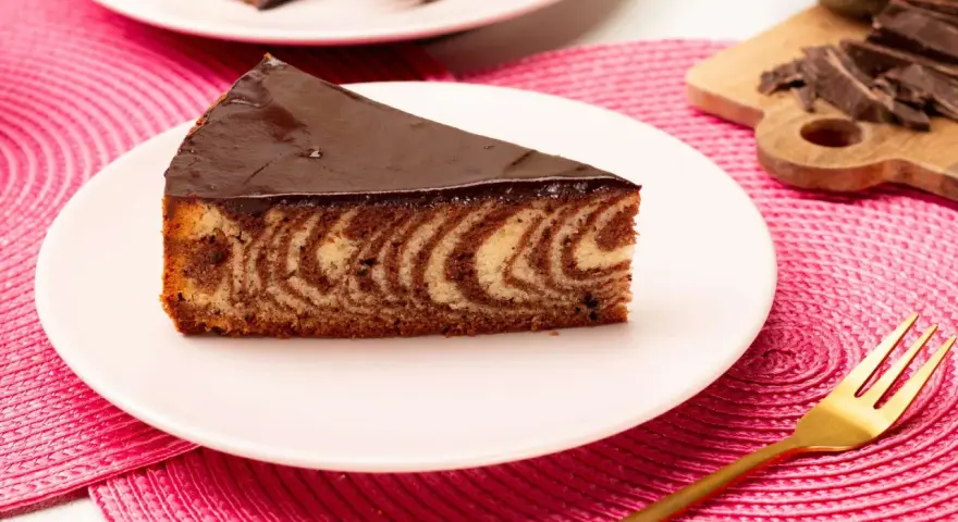 Ein Stück saftiger Zebrakuchen mit Schokoladenglasur auf einem Teller. Dieses Zebrakuchen Rezept ist ein Klassiker.