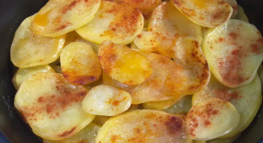 Rodajas de patatas fritas al horno, doradas y espolvoreadas con pimentón.