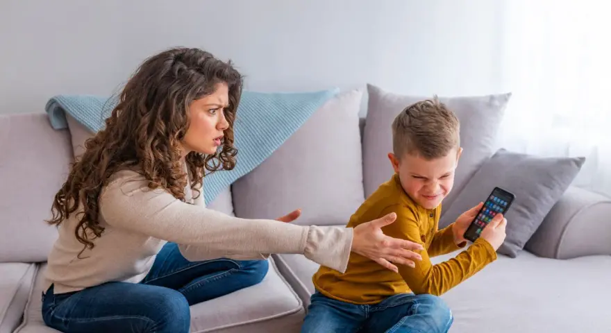 Genervte Mutter streitet mit Sohn, der sein Handy nicht abgeben will. Mögliche ADHS-Erziehungsfehler im Fokus.