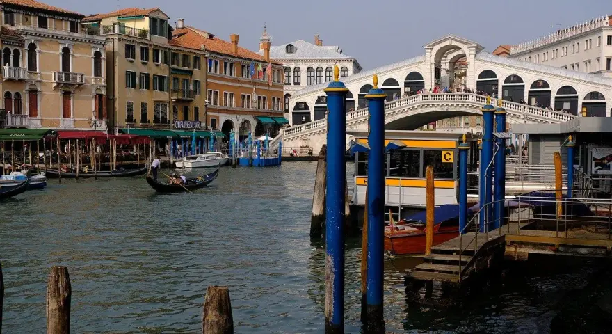Gondola scivola sul Canal Grande, con il Ponte di Rialto e il vivace mercato di Rialto sullo sfondo.