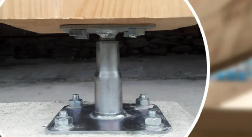 Metalowa kotwa do słupa drewnianego zamontowana na betonowym fundamencie.