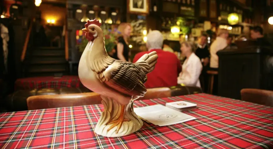 Keramikhähnchen auf kariertem Tisch in uriger Berliner Kneipe.