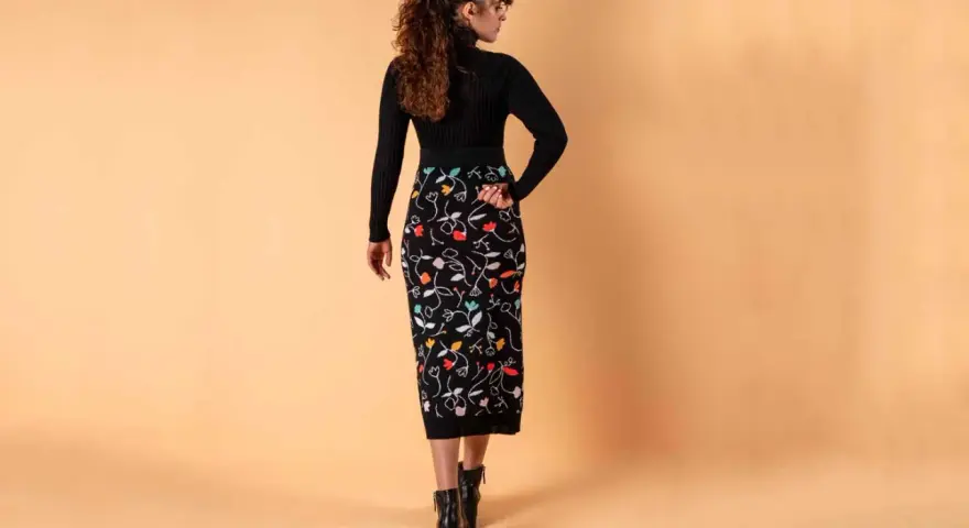 Mujer con falda lápiz negra estampada con flores de colores. Un ejemplo de los diversos tipos de faldas.