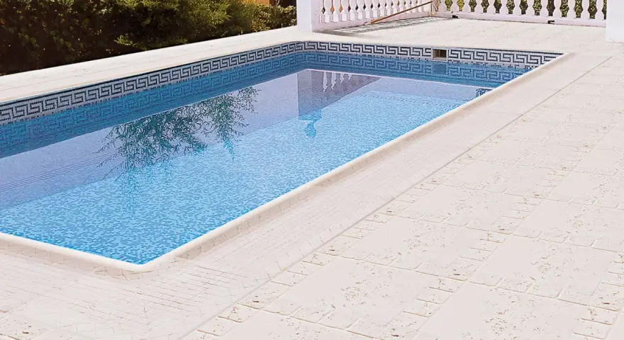 Piscina con borde de mosaico y suelos para piscinas que no quemen, de color claro y textura agradable.