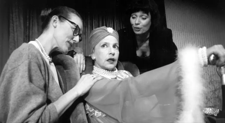 Marlena Milwiw młoda, w otoczeniu dwóch kobiet, w teatralnej scenie.