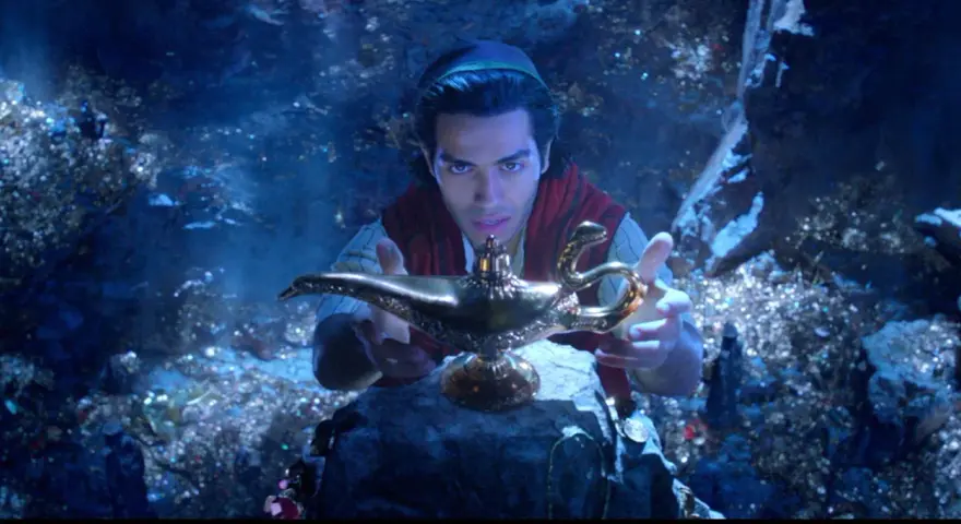 Aladyn, w mrocznej jaskini pełnej skarbów, trzymając magiczną lampę.