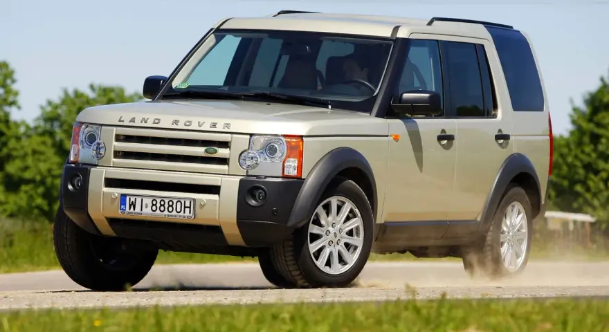 Złoty Land Rover Discovery 3 w ruchu, unoszący kurz. Temat: land rover discovery 3 awarie i problemy.