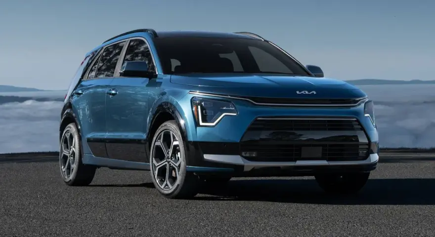 Niebieski Kia Niro Hybrid z nowoczesnym designem, zaparkowany na tle mglistego krajobrazu.