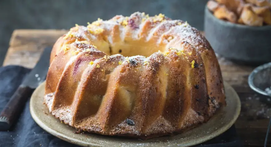 Wilgotna babka piaskowa Ewy Gotuje, posypana cukrem pudrem i skórką cytrynową, wygląda apetycznie.