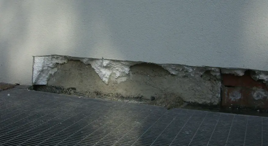 Deterioramento di un muro con esposizione di materiale isolante in eps alta densità e grata metallica sottostante.