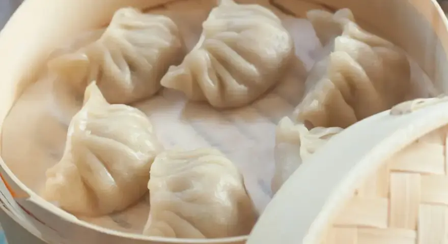 Aksamitne pierożki na parze w bambusowym koszyku, parujące i gotowe do jedzenia.