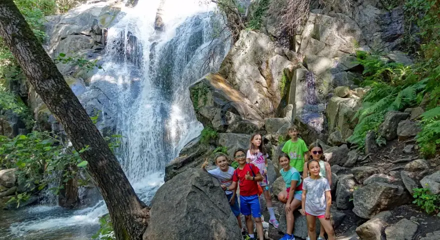 Niños exploran la Garganta de las Nogaleas, disfrutando de una cascada y la naturaleza.