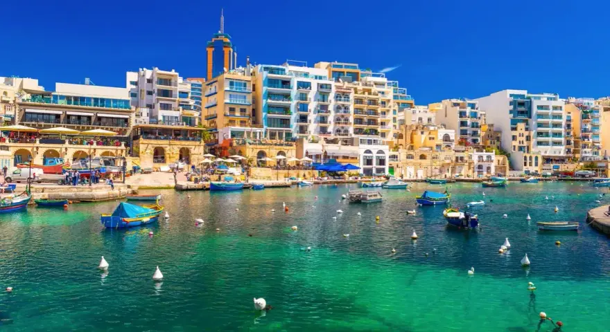 Malta, gdzie na Malcie jest tak pięknie! Woda krystalicznie czysta, łodzie kołyszą się na falach, a w tle kolorowe budynki.