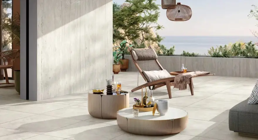 Une **terrasse en travertin** aux tons clairs, avec mobilier de détente et vue mer. Avis : un espace paisible et élégant.