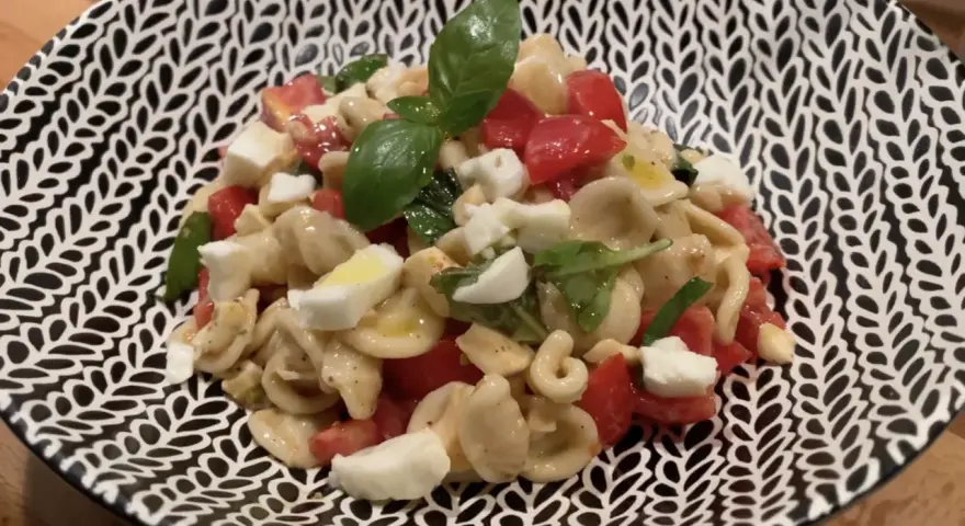 Orecchiette alla crudaiola con pomodorini, mozzarella e basilico fresco, un piatto estivo colorato e saporito.