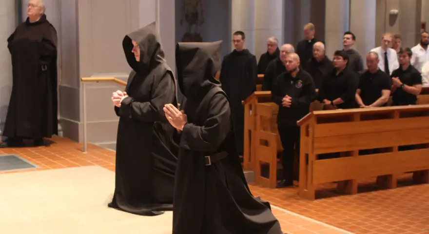 Monk characteristics are evident in the solemn robes and prayerful stances of individuals in a church setting.