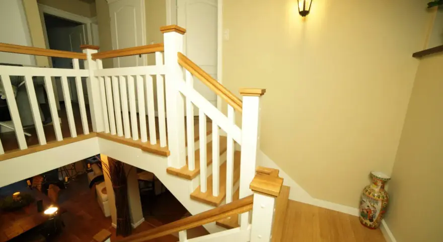 Elegancka klatka schodowa w stylu angielskim z białymi balustradami i drewnianymi elementami.