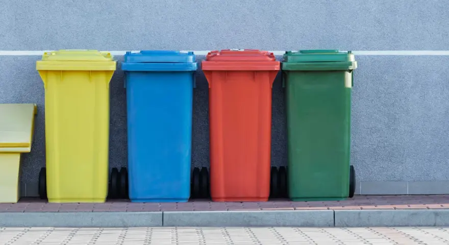 Kolorowe pojemniki na śmieci, w tym żółty, niebieski, czerwony i zielony, stoją obok siebie. Mogą służyć do segregacji odpadów, w tym potencjalnie kod odpadów medycznych igły.