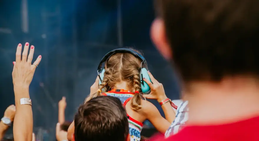 Une jeune fille aux tresses bleues porte un casque anti-bruit pour contrôler le niveau sonore d'un concert.