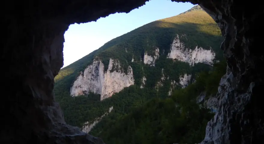 Vista dalla **grotta nera** su un monte verdeggiante con rocce bianche affioranti.