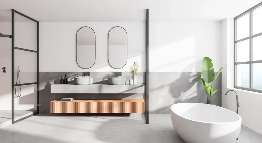 Salle de bain moderne avec baignoire îlot, double vasque et douche. Le sol en béton ciré, un carrelage sans joint, crée une ambiance épurée et contemporaine.