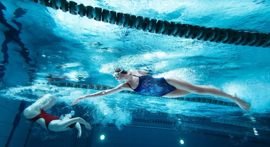 Deux nageuses en action, l'une effectuant une culbute natation, l'autre nageant le crawl sous l'eau.
