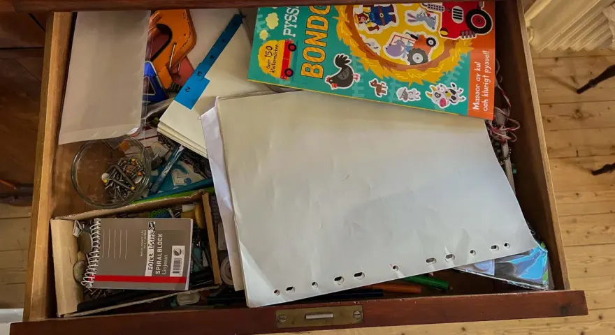 En låda fylld med pysselmaterial, papper, en bok med bondgårdstema och klistermärken, samt en burk med nålar och **påsklämmor**.