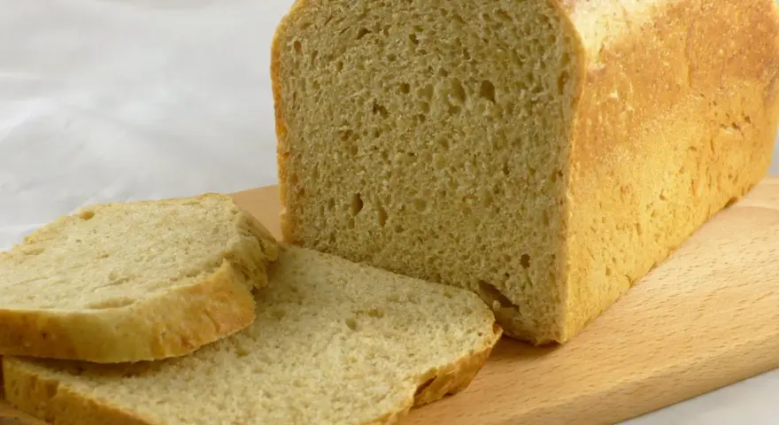 Frisch gebackenes Brot, das wie aus Buchweizen und anderen Getreidesorten gemacht aussieht, liegt auf einem Holzbrett.