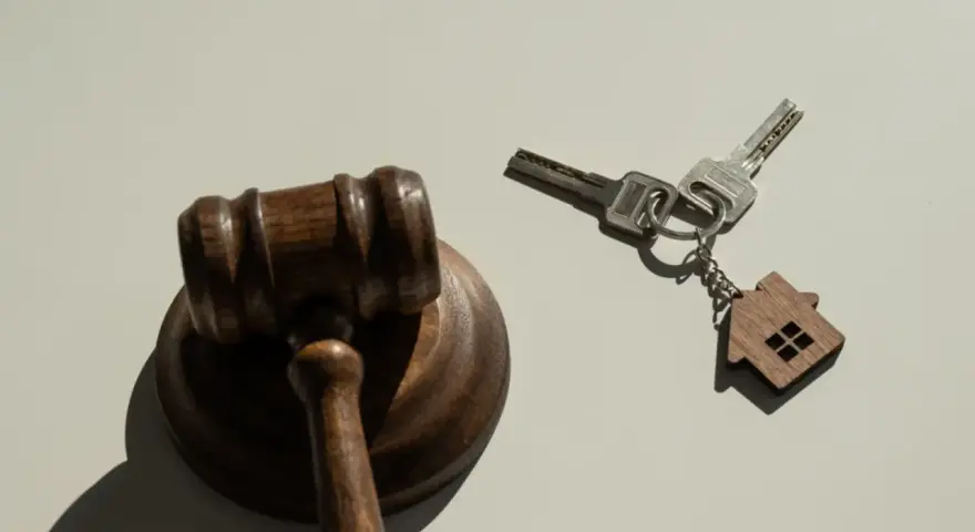 Marteau de juge et clés avec un porte-clés en forme de maison, symbolisant la nouvelle loi sur l'expulsion logement.