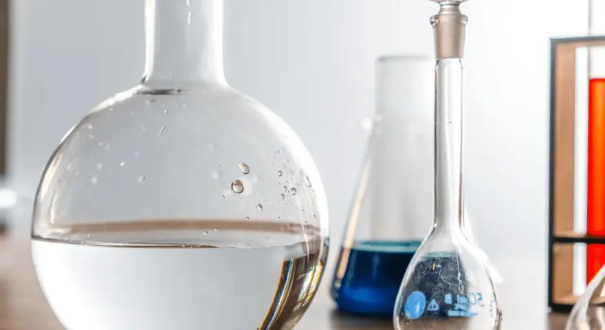Laboratorieglas med vatten och blå vätska. Frågan om man kan dricka destillerat vatten är relevant i vetenskapliga sammanhang.
